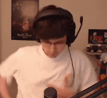 a man wearing headphones and a white shirt stands in front of a microphone