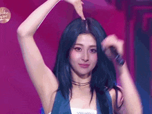 a woman with blue hair is holding a microphone and making a heart shape with her hand .