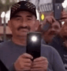 a man with a mustache is taking a selfie with his cell phone .