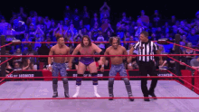 a group of wrestlers are standing in a ring with a referee