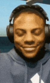 a man wearing headphones and a blue hoodie smiles