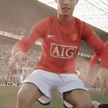 a soccer player wearing a red aig jersey kicks the ball