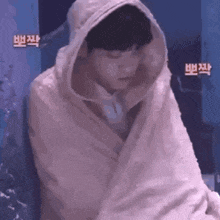 a person wrapped in a pink blanket with a hood on .