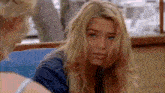 a woman with long blonde hair is looking at the camera while sitting next to another woman .