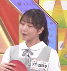 a girl with chinese writing on her name tag is holding a red object