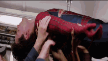 a man in a spiderman costume is being lifted by a group of people