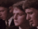 a group of young men are standing next to each other in a row and looking at something .