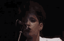 a woman is singing into a microphone on stage .