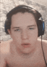 a shirtless man wearing headphones is making a funny face .