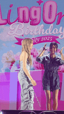 two women standing on a stage in front of a sign that says lingo birthday city 2025