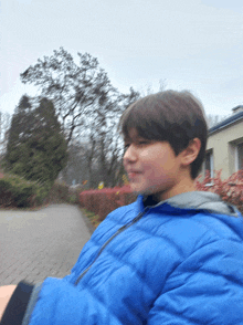 a young boy wearing a blue jacket is walking down a street