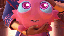 a person is holding a pink stuffed animal with purple eyes