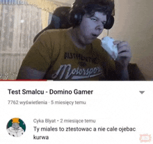 a man wearing headphones is playing a video game and eating a piece of food .