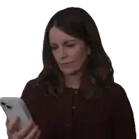 a woman in a maroon sweater is looking at a cell phone