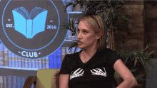 a woman is sitting in front of a screen that says club
