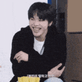 a young man in a black jacket is smiling and holding a bag of chips