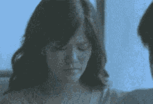 a woman is sitting in front of a window with her eyes closed and a man is standing behind her .