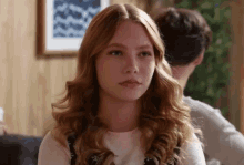 a woman with long red hair looks at the camera