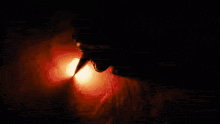 a close up of a person 's mouth with a flame coming out of it in the dark .