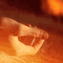 a close up of a person 's hand laying on a rock