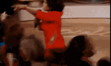 a woman in a red dress is dancing in front of a crowd
