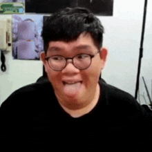 a man wearing glasses and a black shirt sticks his tongue out