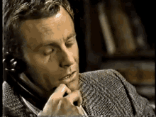 a man is talking on a phone with his eyes closed