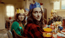 a group of people wearing paper crowns are sitting around a table
