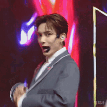a man in a suit with a microphone on his head stands on a stage