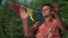 a man in a red shirt is standing in front of a bunch of flags .