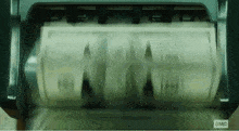 a roll of money is being counted in a machine that says ' a.m.c ' on the bottom .