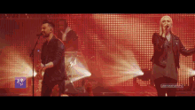 a man and a woman singing on a stage with a sign that says ' a few go '