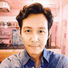 a man in a blue shirt is taking a selfie in a room .