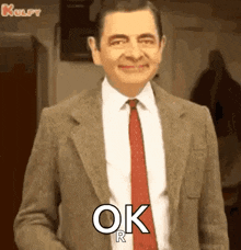 mr bean is wearing a suit and tie and saying ok r .