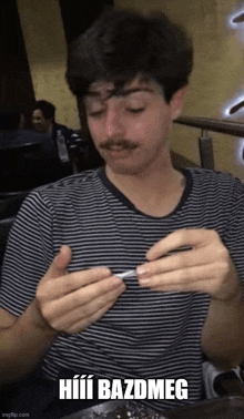 a man with a mustache is holding a cigarette in his hand with the caption hiui bazdmeg on the bottom