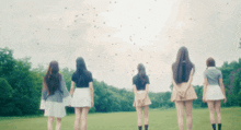 a group of girls are standing in a field with balloons flying in the sky