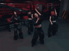a group of women are dancing in a dark room with red boxes in the background