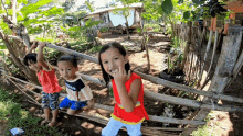 a girl in a red tank top with the word dream on it stands next to two other children