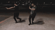 a couple of men are dancing together in a park at night .