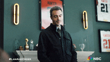 a man in a black jacket stands in front of a framed hunter jersey