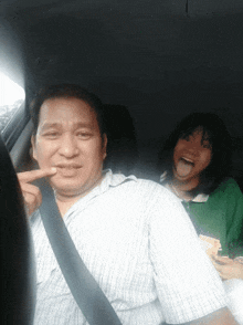 a man and a girl are sitting in a car and the girl is sticking out her tongue