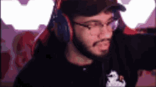 a man with a beard and glasses is wearing headphones and a hat while playing a video game .
