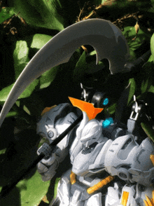 a toy robot with a scythe on its head is sitting in a plant