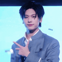 a young man in a blue suit is pointing at something