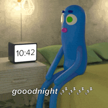 a blue cartoon character is sitting on a bed next to a clock that says 10:42