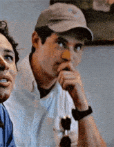 a man wearing a baseball cap is sitting next to another man .