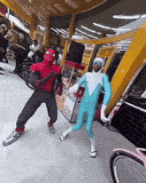 a man in a spiderman costume is dancing with another man in a blue suit
