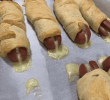 a bunch of hot dogs wrapped in puff pastry with cheese on them