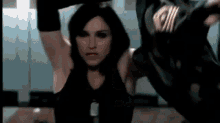 a woman in a black tank top is stretching her arms in a locker room .