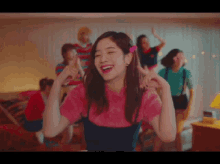 a woman in a pink shirt is dancing with a group of women in a room .